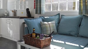 A modern kitchen with white cabinets, a stainless steel range hood, and a window with plaid curtains. - 1 bedroom accommodation in Borrowdale, near Keswick (Borrowdale, near Keswick)