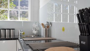 A modern kitchen with a large window, stainless steel appliances, and a knife block. - 1 bedroom accommodation in Borrowdale, near Keswick (Borrowdale, near Keswick)