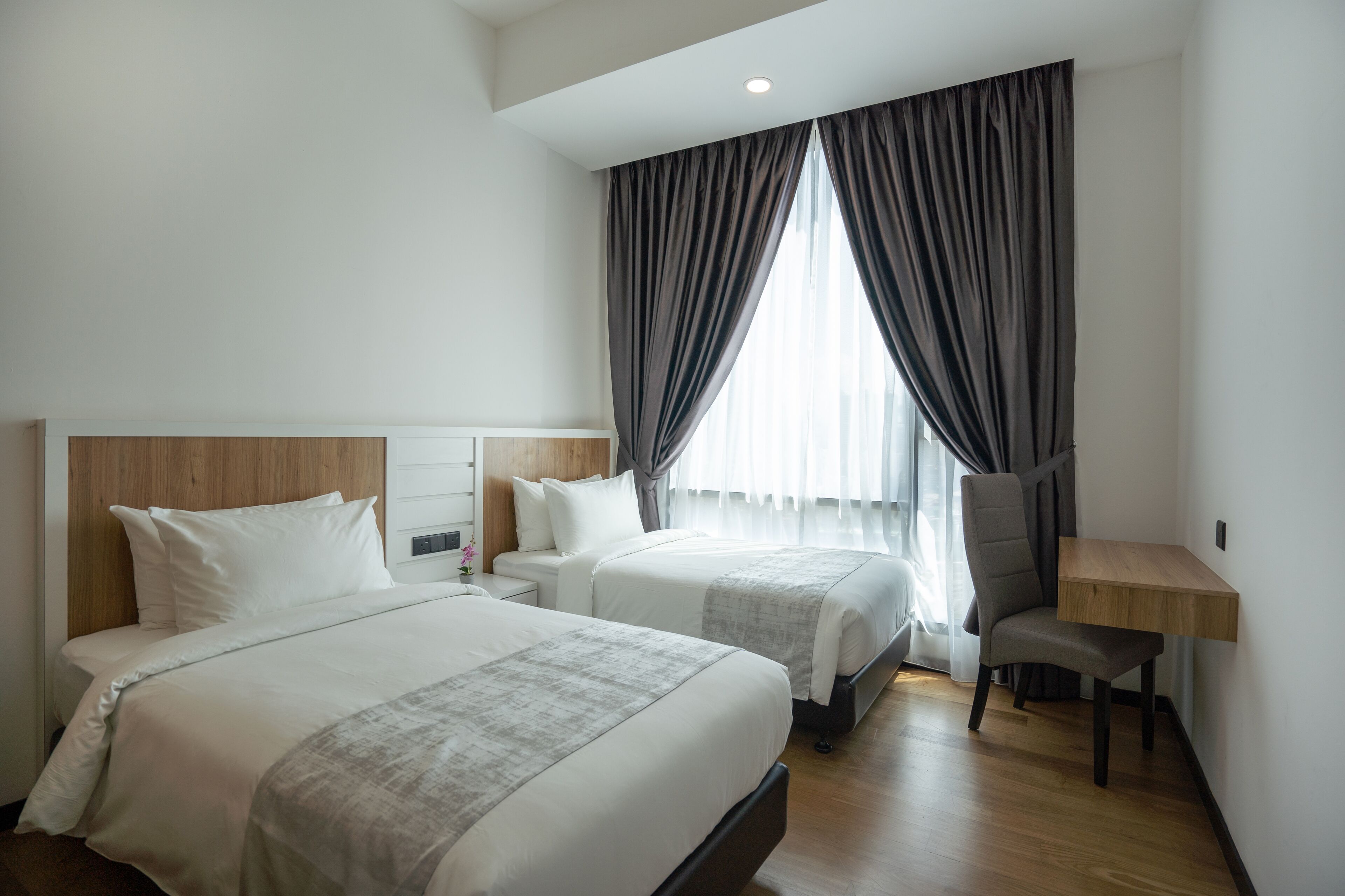 Quarto de hotel com duas camas, uma mesa e uma cadeira.