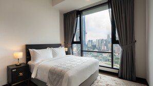 A hotel room with a large bed, a nightstand with a lamp, and a view of a cityscape through a large window. - Opus Residences (Kuala Lumpur)