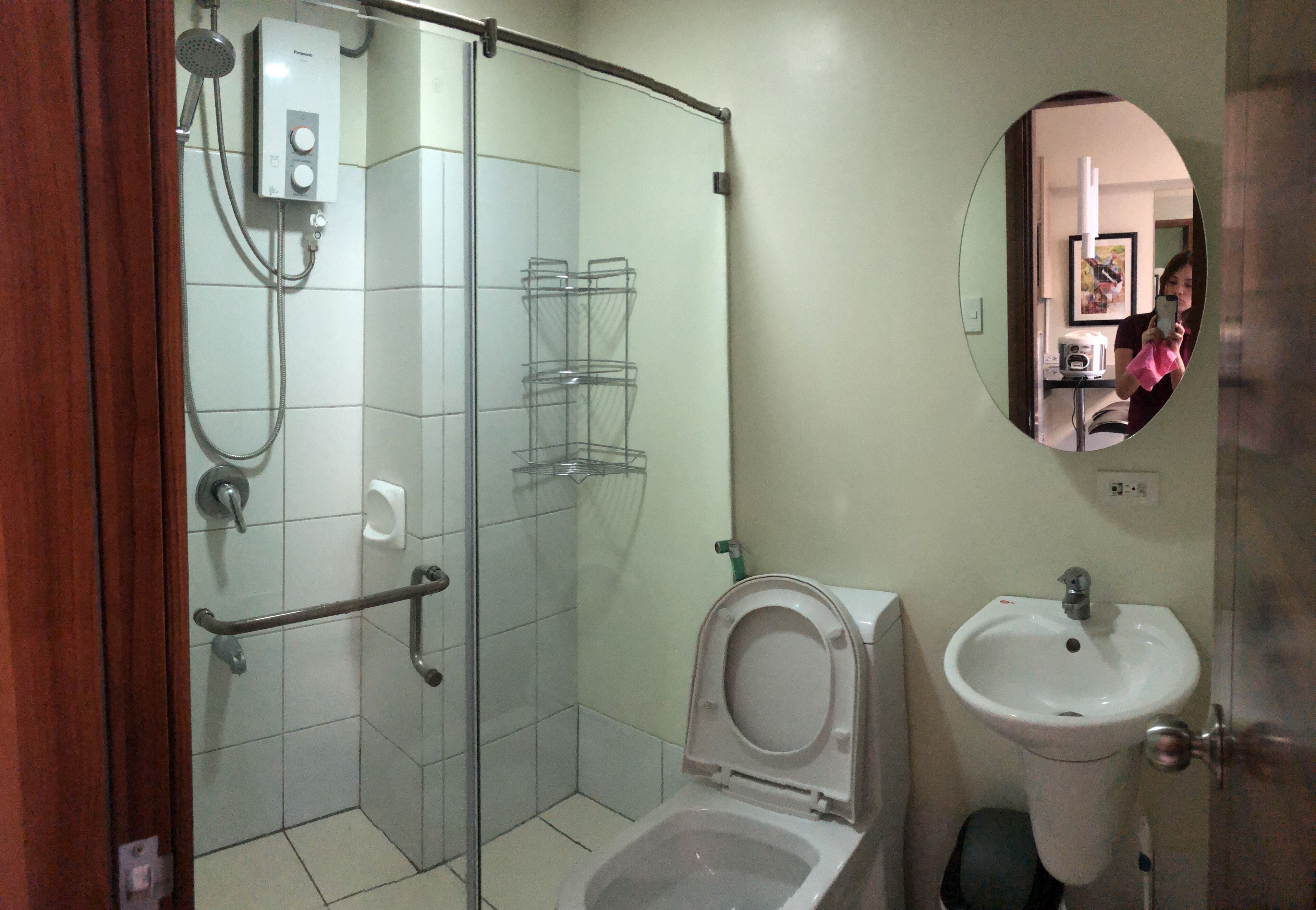 Een badkamer met een douchecabine van glas, een toilet en een wastafel.