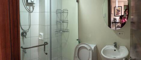 Een badkamer met een douchecabine van glas, een toilet en een wastafel.
