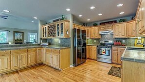A spacious kitchen with wooden cabinets, stainless steel appliances, and a large island. - Exclusive private mountain and lake vacation in the Cohutta wilderness (Ellijay)