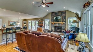 A spacious living room with a large brown leather couch, a fireplace, and a mounted deer head. - Exclusive private mountain and lake vacation in the Cohutta wilderness (Ellijay)