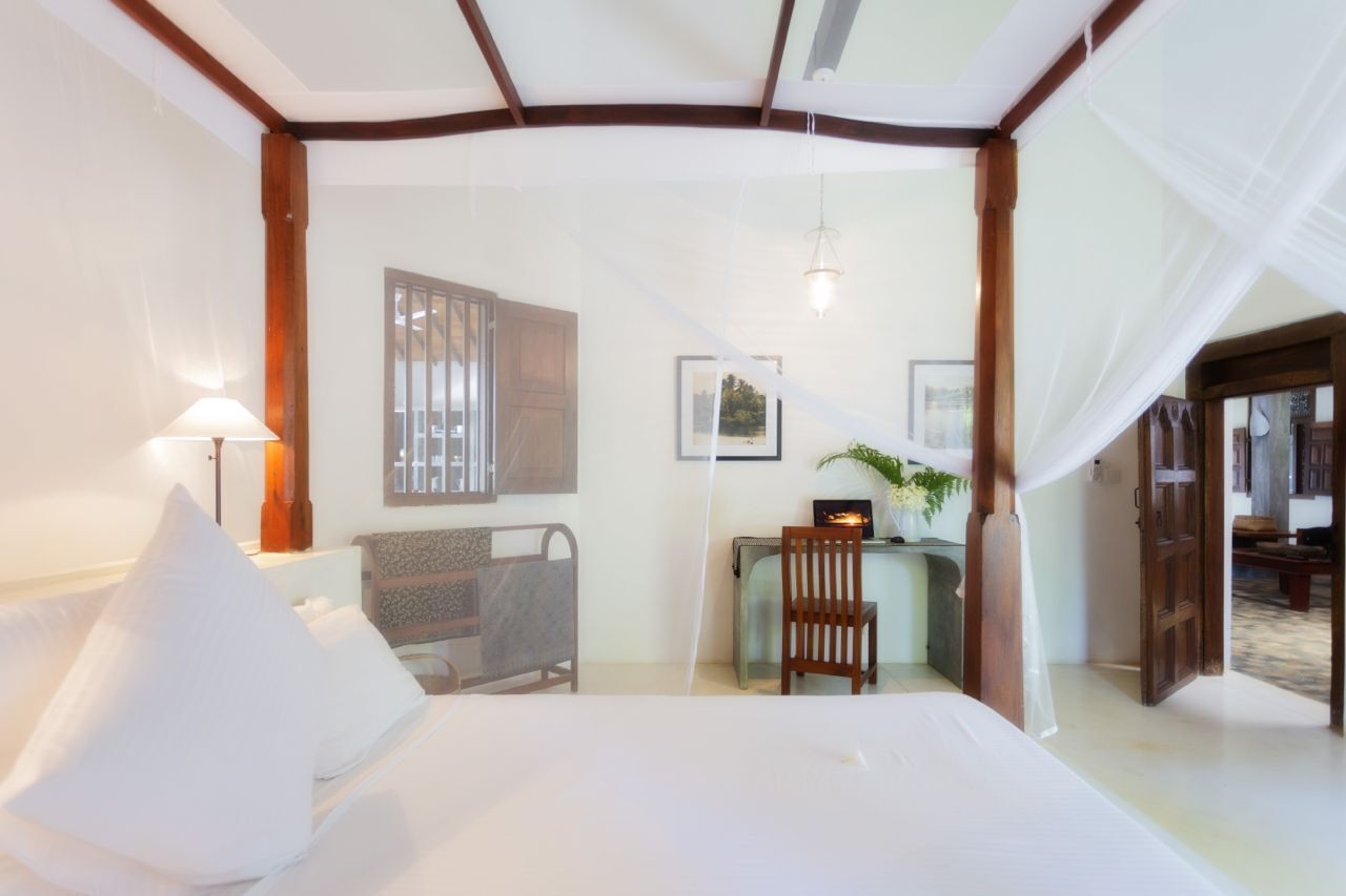 Une chambre à coucher comprenant un lit, une table de chevet, une chaise, un bureau et une fenêtre.