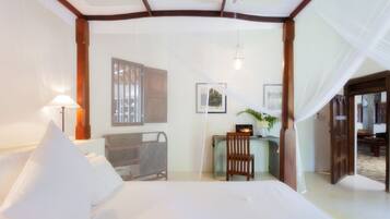 Une chambre à coucher comprenant un lit, une table de chevet, une chaise, un bureau et une fenêtre.