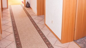 Un pasillo con una puerta de madera, un espejo y un reloj en la pared.