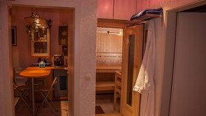 Un pasillo estrecho que conduce a un sauna de madera con un banco y una toalla colgada en la pared.