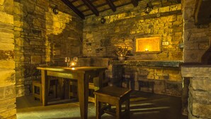 A stone-walled room with a wooden table and bench, a lit wall-mounted lamp, and a potted plant. - VILLA SALVIA**** Rakalj  (Rakalj)