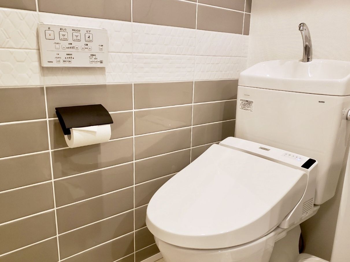 A modern bathroom with a toilet, a paper towel dispenser, and a sink.