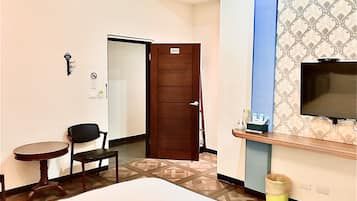 Een hotelkamer met een bed, een bureau, een stoel, een televisie en een deur.