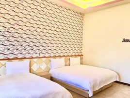 Quarto de hotel com duas camas, papel de parede estampado e um letreiro com a palavra 'Home'.
