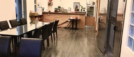 A modern kitchen with a dining area, featuring a large table, chairs, and a counter with various appliances and decorations.