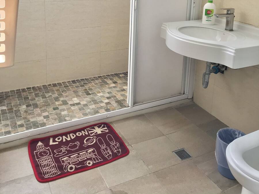 A bathroom with a shower, sink, and a London-themed mat.