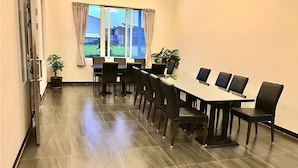 A conference room with a long table, chairs, potted plants, and a large window with curtains. - Min Min Bed and Breakfast (Chishang)