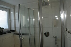 Deluxe tweepersoonskamer | Badkamer | Een douche, een haardroger, handdoeken