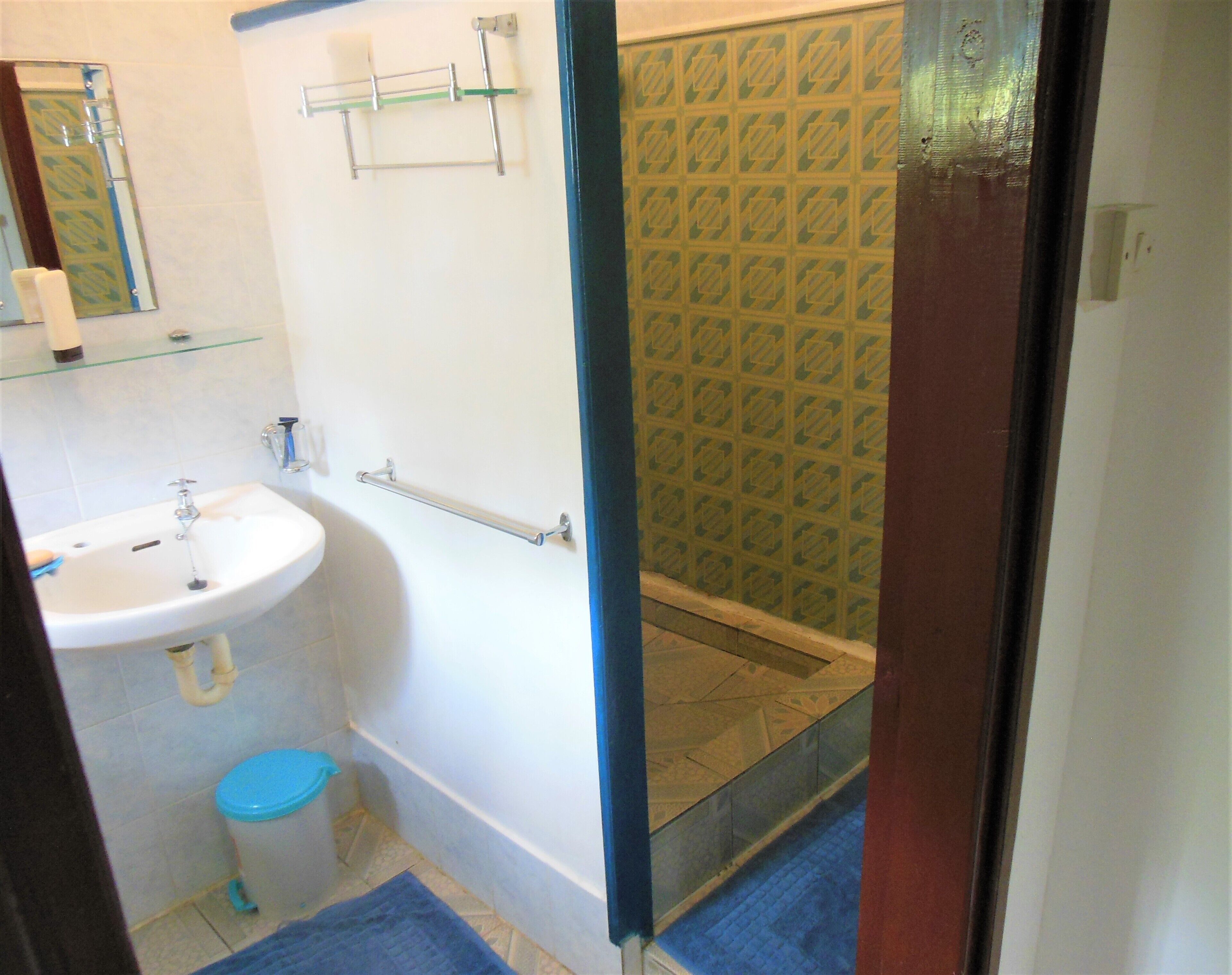 A bathroom with a sink, mirror, towel rack, and shower.