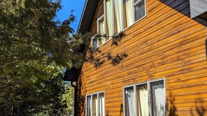 A two-story wooden house with a patio area, outdoor furniture, and a barbecue grill. - Cedar Loft on Lake Michigan (Naubinway)