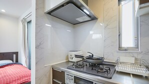 A compact kitchen with a stove, a rice cooker, and a window. - Jay and Lan's Himawari house (Tokyo)