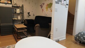 A living room with a sofa, a coffee table, a bookshelf, and a world map on the wall. - Jay and Lan's Himawari house (Tokyo)