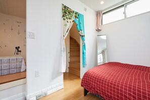 A bedroom with a red bedspread, a staircase, and a window with curtains. - Jay and Lan's Himawari house (Tokyo)