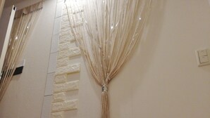 A wall with a textured stone pattern and a decorative tassel hanging from the ceiling. - Jay and Lan's Himawari house (Tokyo)