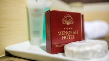 Una pastilla de jabón con la marca Menorah Hotel y una caja roja con el logo del hotel sobre una bandeja blanca.
