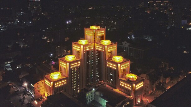 A high-rise building with multiple illuminated floors, surrounded by other buildings. - Menorah Hotel (Dnipro)