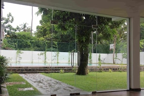 Un interior moderno con amplios ventanales que dan a un jardín con piscina.