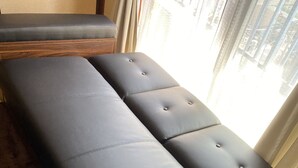 A room with a large, dark-colored sofa and a wooden bench. - Shibuya Japanese-style room 2DK small up to family 4 parsons + Pocket Wifi (渋谷区)