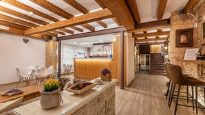 A cozy interior with a wooden ceiling, a reception desk, and a staircase leading to an upper level. - Hostal 977 (Tarragona)