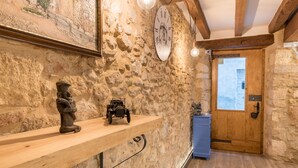 A rustic interior with stone walls, a wooden door, and a shelf with a statue and a model car. - Hostal 977 (Tarragona)