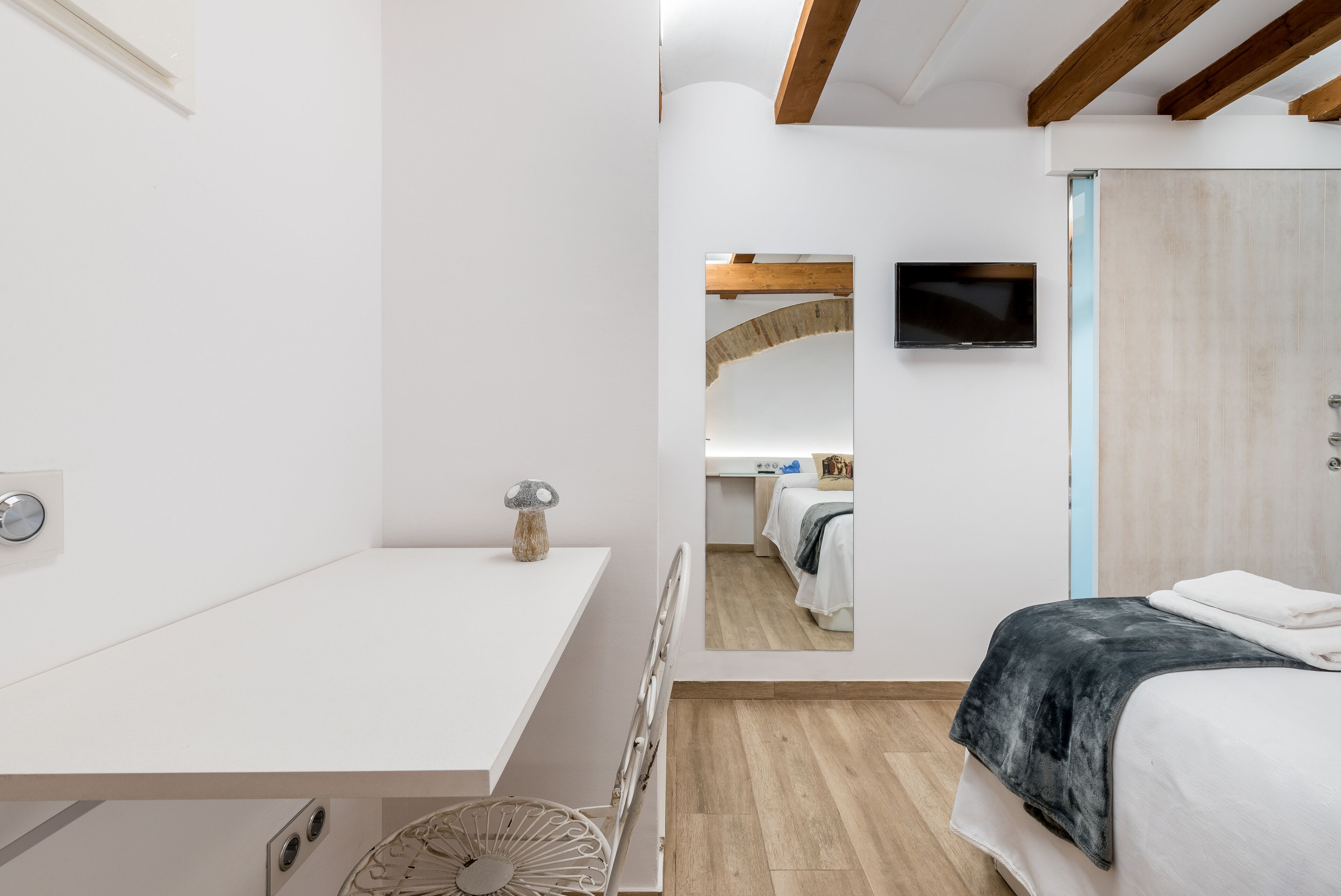 Un dormitorio moderno con cama, mesita de noche y televisor montado en la pared.