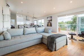 A modern living room with a sectional sofa, a dining area, and a kitchen.