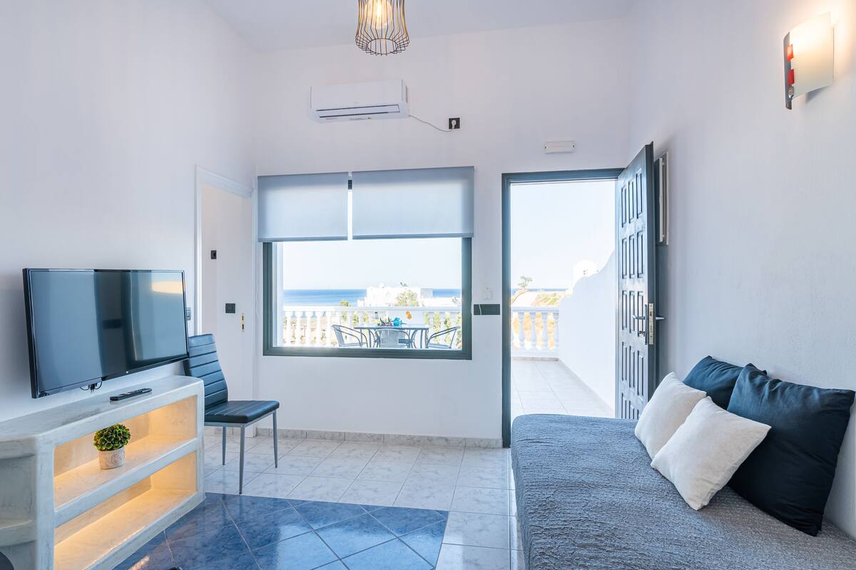 Una habitación moderna con televisión, zona de estar y balcón con vistas.