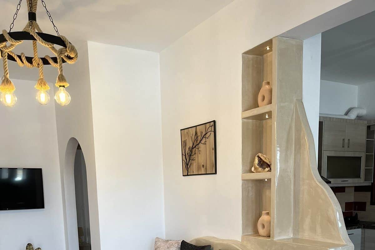 Una sala de estar moderna con un sofá curvo, un televisor de pantalla plana, una lámpara decorativa y un diseño minimalista.