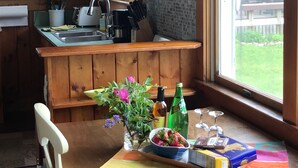 A wooden kitchen with a window, a sink, and a dining area with a table set for two. - Ocean Front Cottage! (Westport)