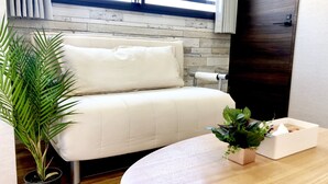 Een moderne kamer met een witte bank, een ronde houten tafel en een plant in pot.