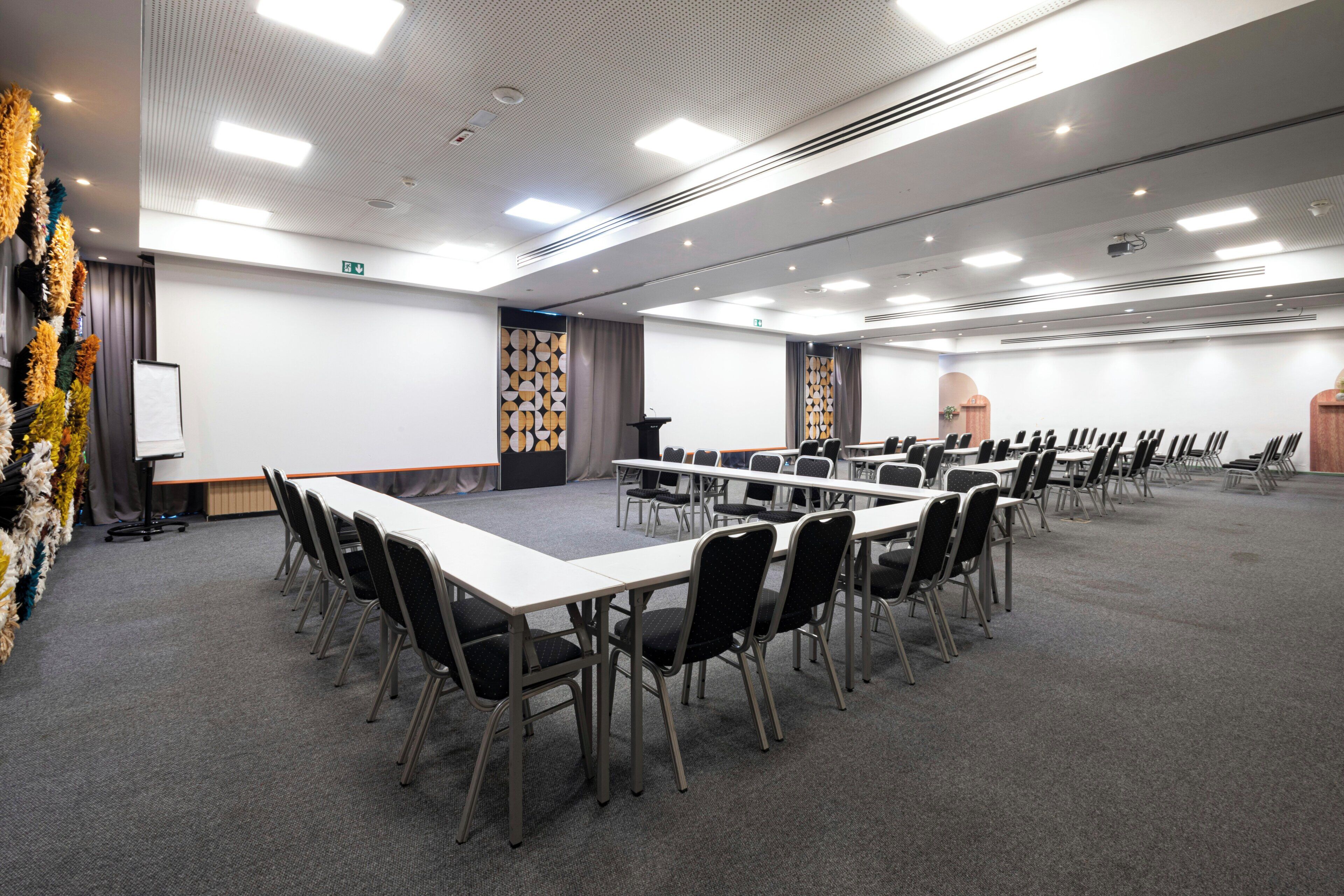 A conference room with a long table, chairs, a podium, and a whiteboard.