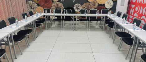 A conference room with a long table and chairs, a decorative wall with a 'Come experience' sign, and an air conditioning unit.
