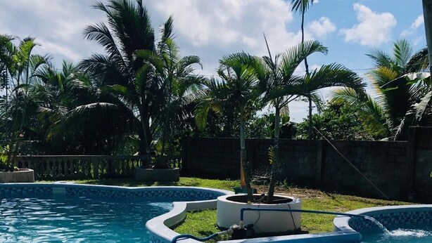 A swimming pool with a tiled edge and a small water feature. - Jupiter's Garden Resort (Lawaan)