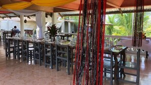 An outdoor dining area with tables and chairs, a hanging decorative element, and a view of greenery. - Jupiter's Garden Resort (Lawaan)