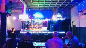 A bar with a counter, stools, and a TV screen. - Jupiter's Garden Resort (Lawaan)