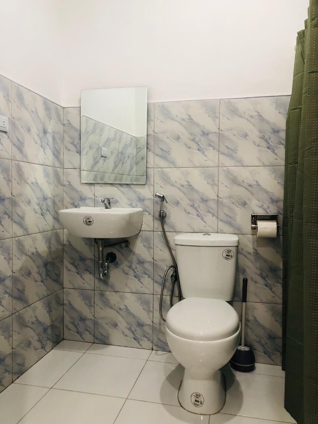 Un baño con lavamanos blanco, inodoro y espejo sobre el lavamanos.