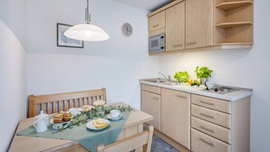 Uma cozinha compacta com armários de madeira, um micro-ondas e uma área de refeições com mesa posta para dois.