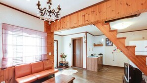 A cozy living room with a wooden staircase, a sofa, a coffee table, and a television.