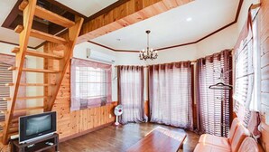 A wooden interior with a sofa, a wooden table, and a TV on a stand.