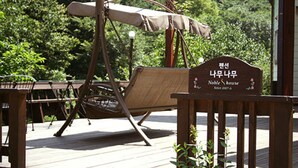 A wooden deck with a swing chair and a sign reading "Noble House Since 2007".