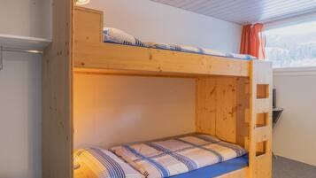 Un lit superposé avec une structure en bois, un matelas bleu et des oreillers à rayures.