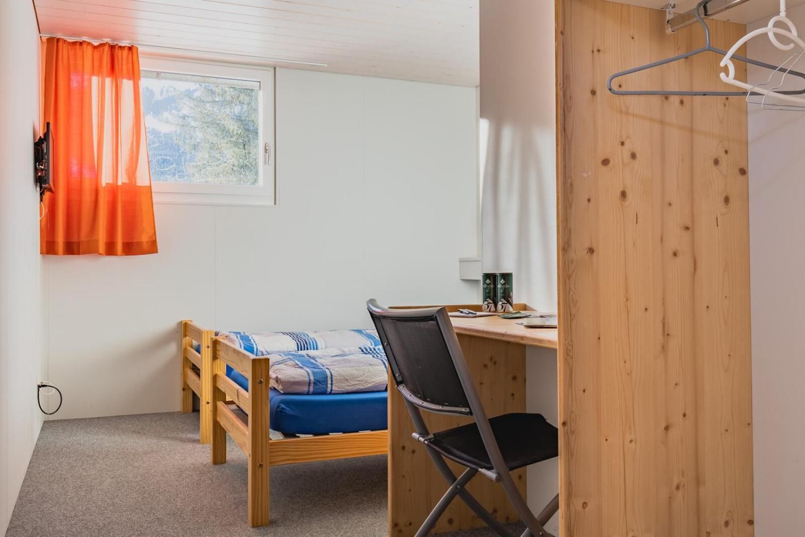 Une petite chambre avec un lit simple, un bureau et une chaise.